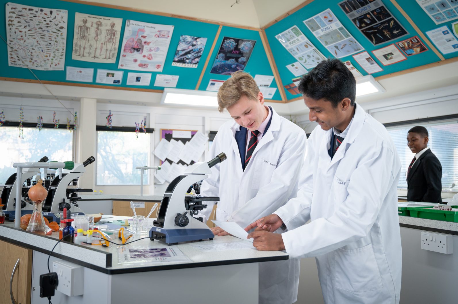 Magdalen College School pupils studying science and using a microscope.